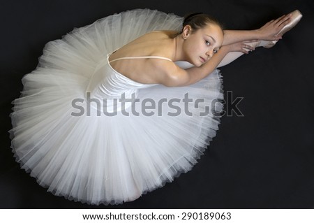 Young ballerina in white ballet tutu is dancing on a white background