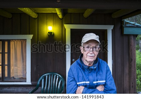 Elderly man in his 80s standing by a cabin
