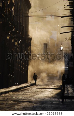 Person sweeping a cobblestone street, Mexico.