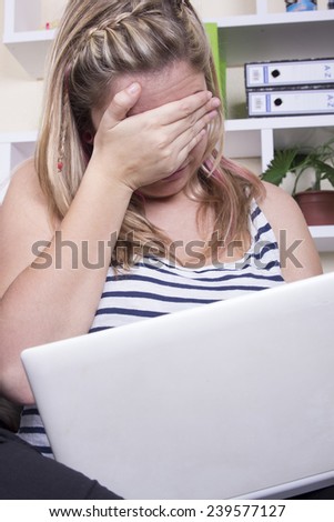 Sad girl using computer covering his eyes