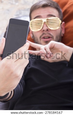 Guy taking selfie on sofa wearing gold glasses