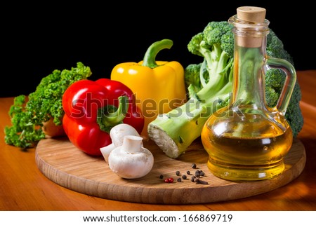 fresh vegetables with bottle of oil on cutting board, still life