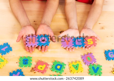 Colorful foam puzzle letters words yes and no in kid\'s hands on wooden background