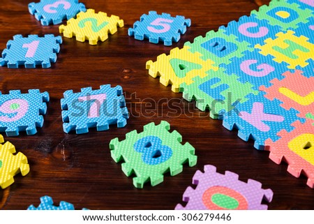 Colorful foam puzzle letters on wooden background, education concept