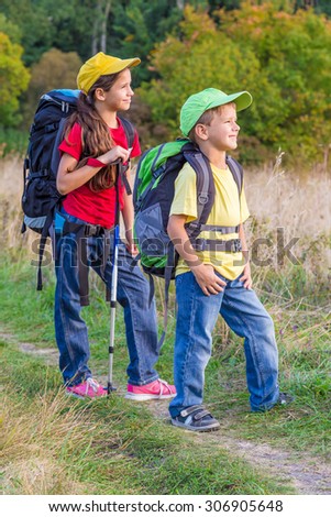 Two kids with backpacks traveling through a meadow