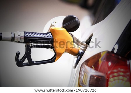 Gas station pump. Man filling gasoline fuel in green car holding nozzle. Close up.