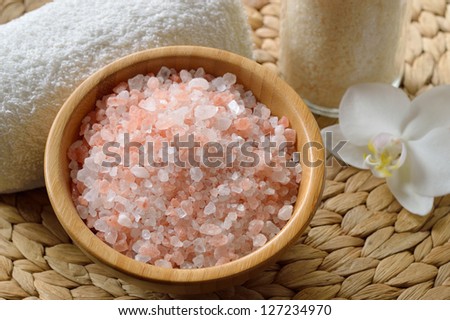Pink salt from the Himalaya. Closeup of pink SPA salt in wooden bowl with orchid flower and towel.