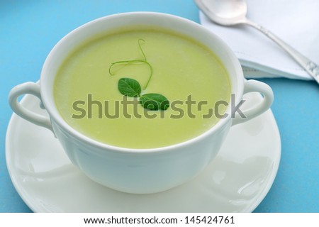 Cold creamy green pea soup with buttermilk and leak and potato. Green soup garnished with pea tendril. Summer meal.