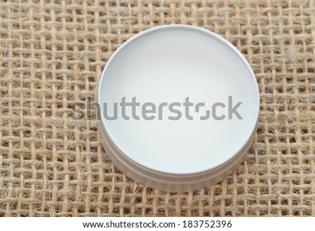 Pure shea butter in metallic tin on linen canvas background. Perfect lip balm and beauty balm.