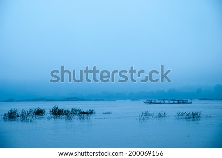 longtail motor boat running in blue tropical waters with fog