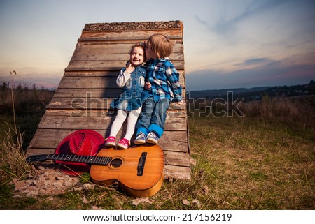 lovely boy and girl with guitar at rural sunset