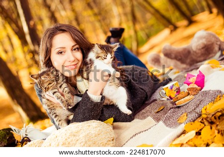 lovely young brunet with two little cats at fall season forest
