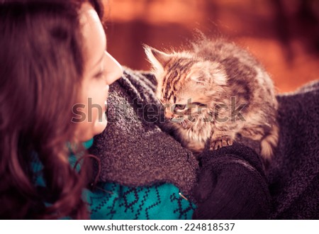 happy lady smiling to little cat on her coat