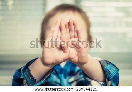boy with hands in front of face