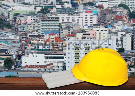 safety helmet and architect plant on wood table with  and building background.