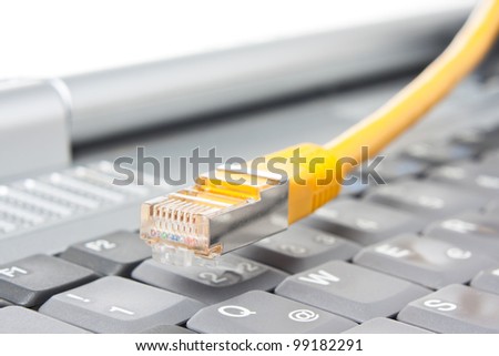 Macro of a yellow network cable in front of a computer keyboard