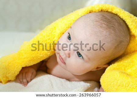 smiling baby looking at camera under a yellow blanket/towel