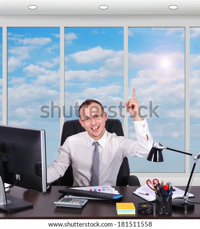 happy businessman sitting in office and pointing up