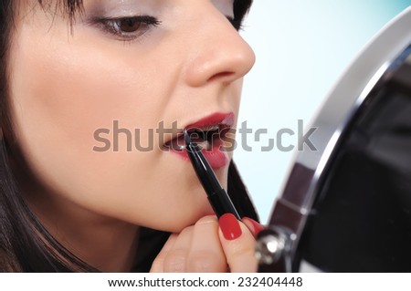 woman applying lipstick with a brush on lips