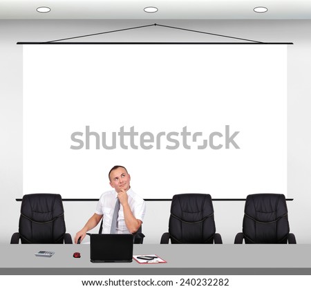 businessman sitting in office with big poster on wall