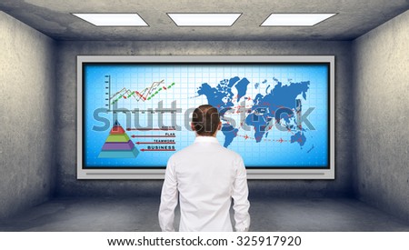 businessman looking at plasma tv with chart and international flights scheme