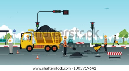 Workers are repairing road surfaces with traffic lights.