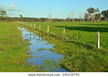 green farmland with fence and water filled channel