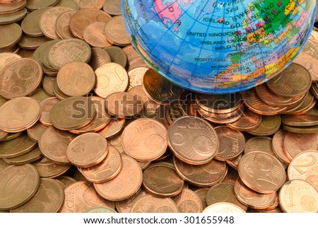 A toy globe, sits on a bed of copper coins. A metaphor on world finance and debt.