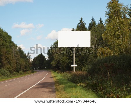 Blank billboard on empty road passing through the forest.