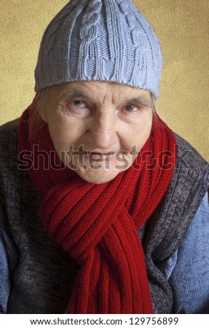 Portrait of a smiling elderly woman with blue cap and red scarf.