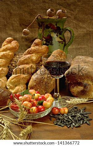 Still life with bread, cherry, and wine on wooden table.