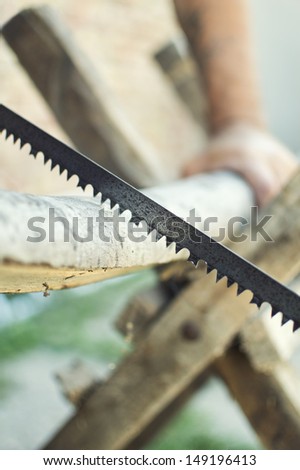 Hand cutting wood with hand saw. Selective focus with shallow depth of field.