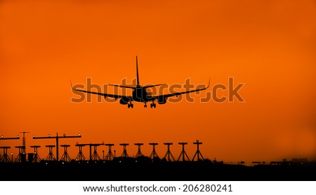 Silhouette of an airplane landing at dusk.