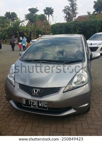 BANDUNG, WEST JAVA, INDONESIA- SEPTEMBER 15, 2014 : Honda Jazz parked in front of a popular tourist attraction location in Bandung, Indonesia. Honda Jazz also known as Honda Fit in Japan.
