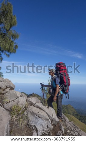 RINJANI MOUNTAIN, LOMBOK, INDONESIA-JUNE 11,2015: Mountain guide AB Pramono with trekking pole walks slowly on trekking path on the way to Rinjani Mountain in Lombok, Indonesia.
