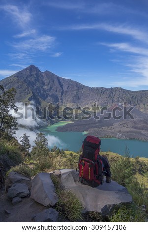 A mountain hiker or trekker takes a break to enjoy beautiful view on top of a mountain.