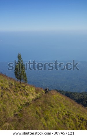 Unidentified mountain hikers or trekker walks slowly on trekking path on the way to Rinjani Mountain in Lombok, Indonesia.