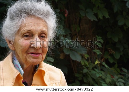 Smiling senior woman on green leaves background