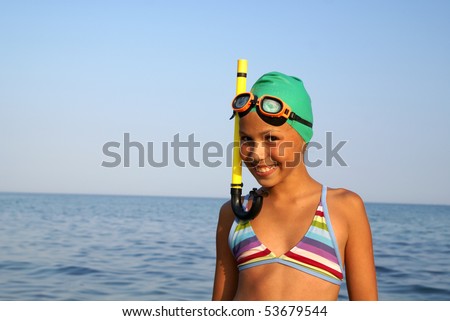 Cheerful preteen girl in diving outfit enjoying sun-bath on sea beach