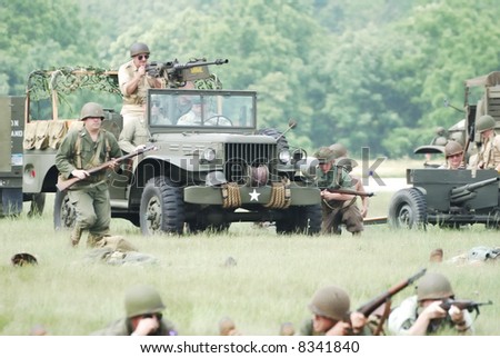 A World War 11 battle reenactment featuring a U.S. Army Jeep and troops.