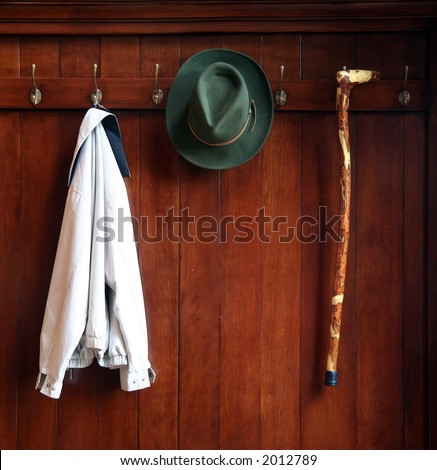 Still life od a wooden clothes rack with a hat,jacket and a cane