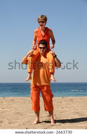 Couple in orange clothes having fun on the beach