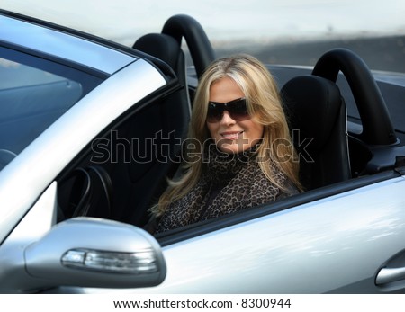 Blond girl in sunglasses driving convertible car