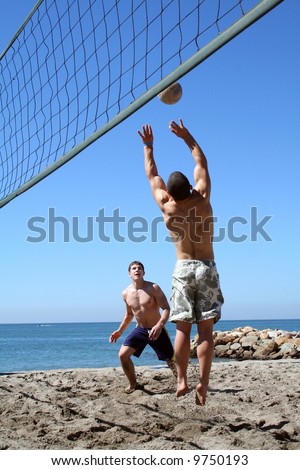 Young men playing volleyball on the beach