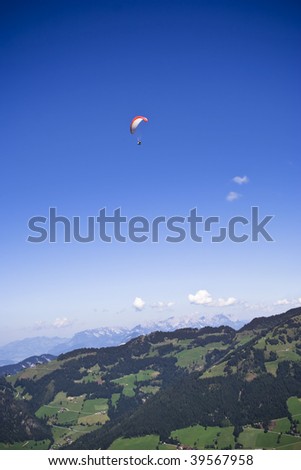 paraglider high up in the air, flying over alpine landscape