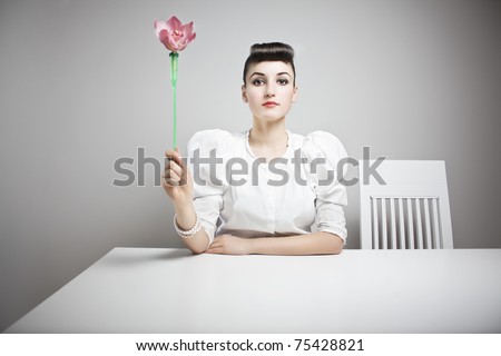 retro styled woman holding an orchid in a white, sterile environment