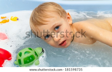 child in water in foam with toys