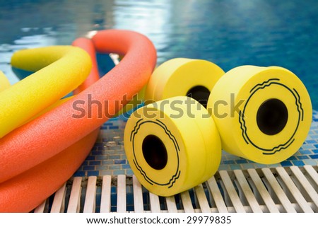 aqua noodles dumbbells for aqua aerobics lie on the coast in pool