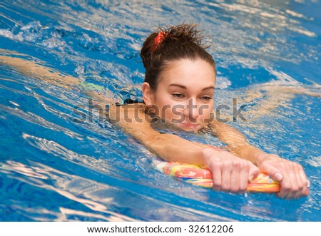 girl learn to swim with board in the swimming pool