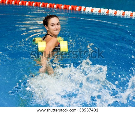 aqua aerobic, woman in water with dumbbells splashes water